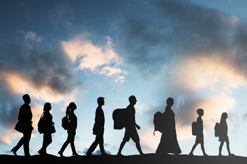 Im Vordergrund sind Silhouetten von acht hintereinanderlaufenden Personen. Hinter ihnen ist ein blauer Himmel mit Wolken. 