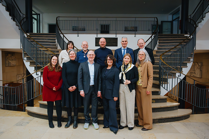 Mehrere Personen stehen vor einer Treppe und posieren für ein Foto.