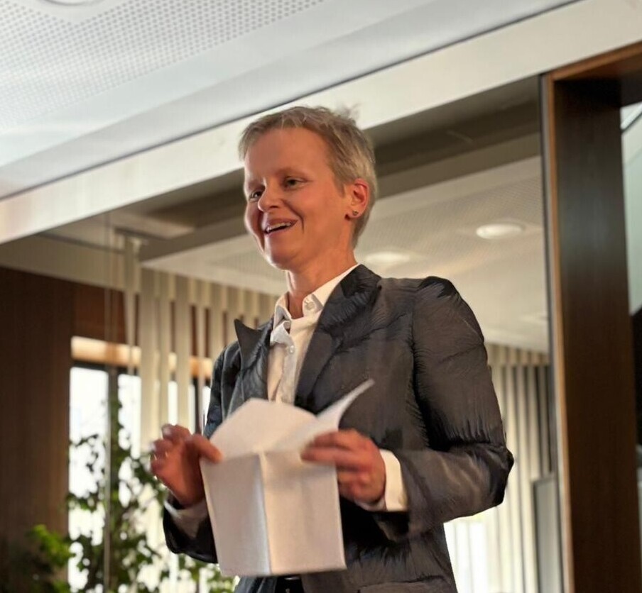 Prof. Dr. Ruhe spricht vor Publikum und hält lächelnd einen Zettel in der Hand.
