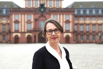 Portraitfoto von Sabine Sonnentag vor dem Mannheimer Schloss. Sie trägt eine Brille, weiße Bluse und schwarzen Blazer.