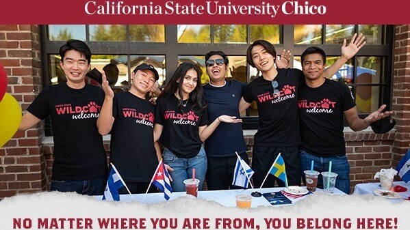sechs Studenten (5 Männer, 1 Frau) stehen vor einem Tisch vor dem Gebäude und grüßen glücklich in die Kamera und heißen einen willkommen, darüber steht California State University Chico (weiße Schrift auf rotem Untergrund)