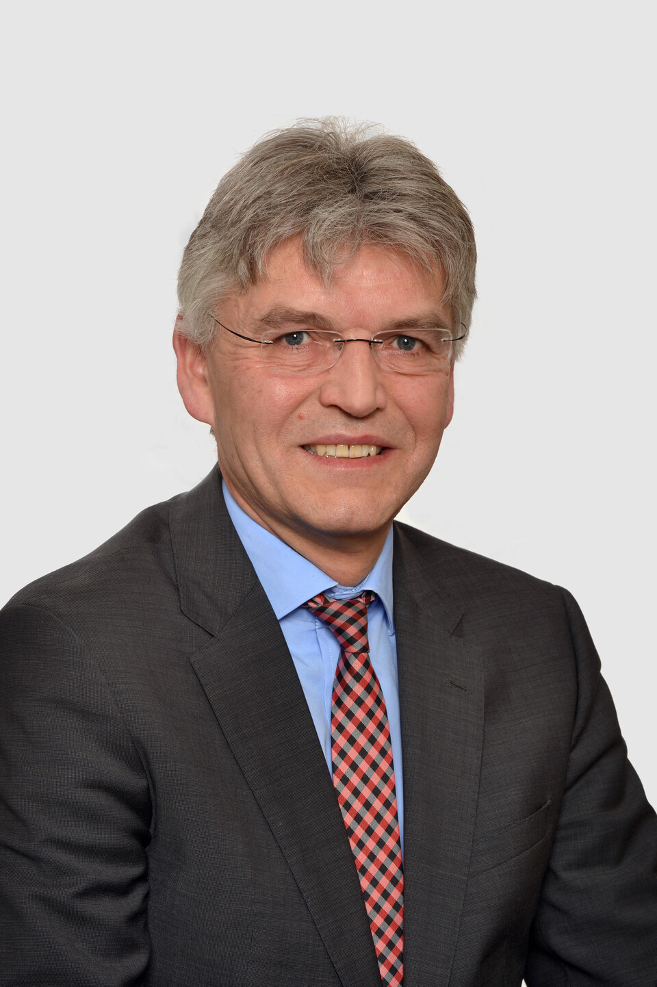 Prof. Spengel hat kurze graue Haare und eine Brille. Er trägt ein dunkles Jacket mit blauem Hemd und einer rot gemusterten Krawatte.