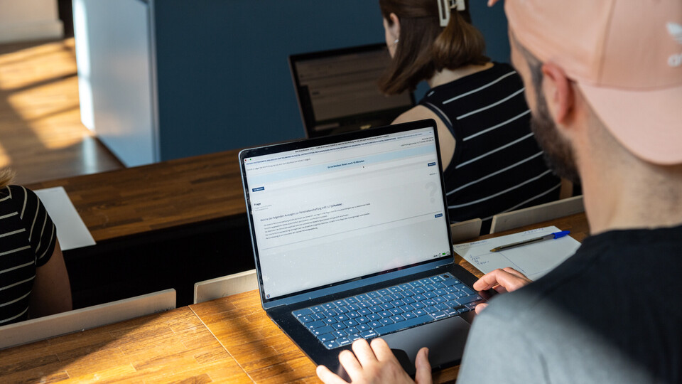 Person am Schreibtisch, die an einem Laptop arbeitet