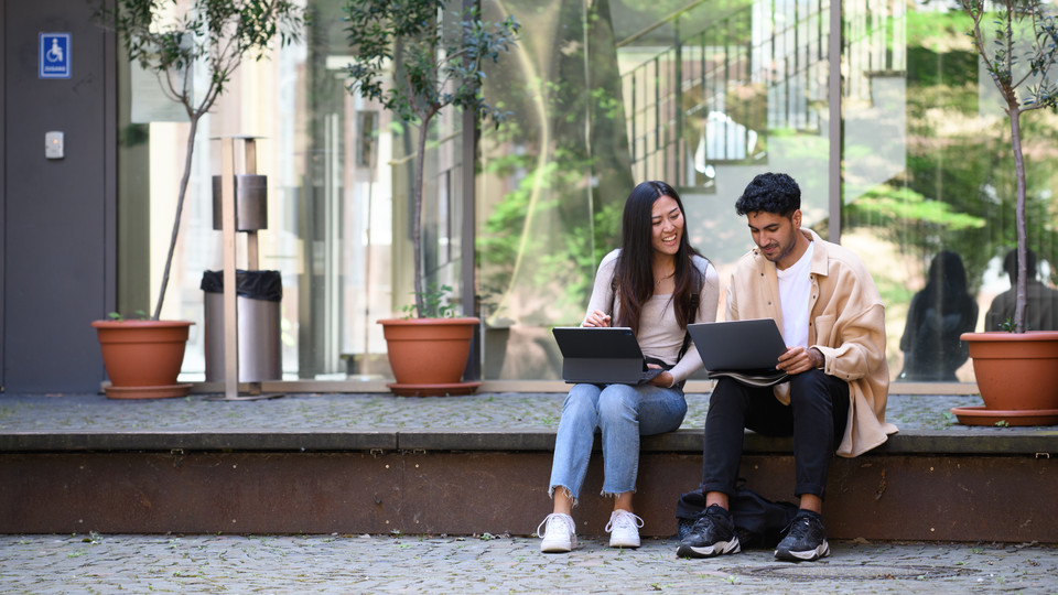 Zwei Studierende arbeiten an ihren Laptops.