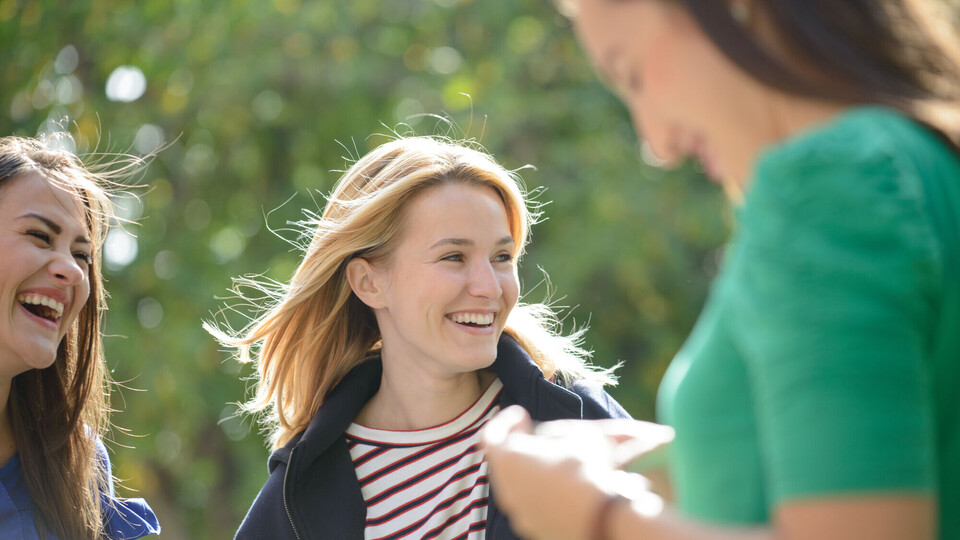 Studentinnen auf dem Campus drei Studierende lachen