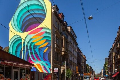 Buntes, großflächiges Mural aus geometrischen Formen. Es erstreckt sich über die gesamte Hauswand eines Hauses im Mannheimer Stadtteil Neckarstadt West. Link: Instagram ENGAGE.EU Event