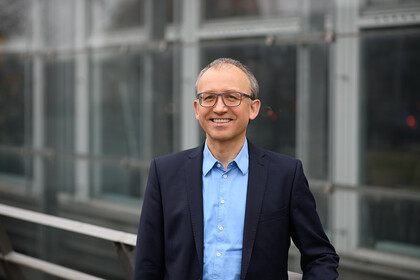 Portrait of Professor Thomas Gschwend, Ph.D. He is wearing a blue shirt with a dark jacket over it and is leaning against a railing.