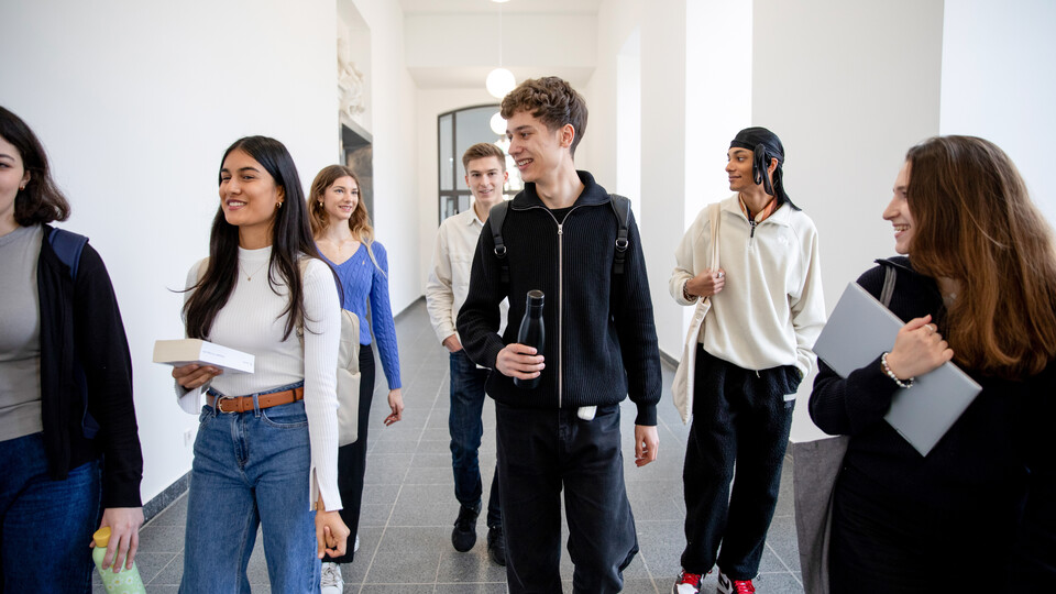 Bachelor Studierende im Ostflügel Gruppe Studierender laufen einen Flur im Schloss entlang und unterhalten sich