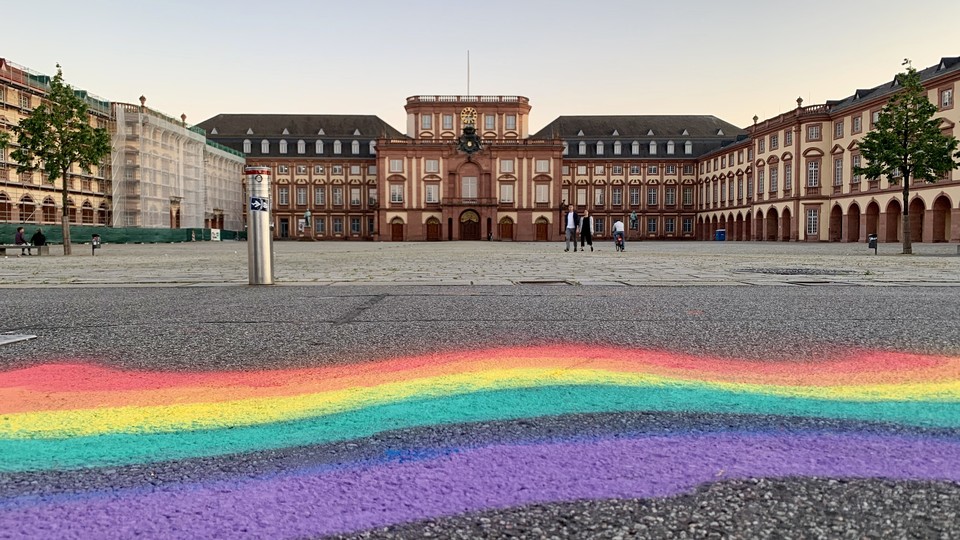 Ein Regebogen ist mit Kreide oder Sprühfarbe auf den Asphalt vor dem Ehrenhof gemalt.