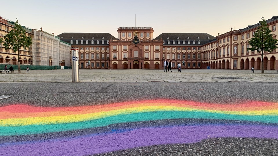 Ein Regebogen ist mit Kreide oder Sprühfarbe auf den Asphalt vor dem Ehrenhof gemalt.