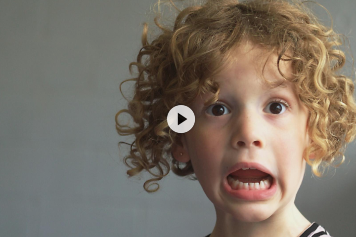 Kind schaut ängstlich in die Kamera. Es hat kurze blonde Locken 