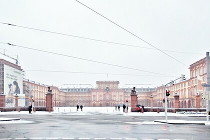 Ferner Blick auf die Universität Mannheim. Es liegt viel Schnee und ein paar Personen betreten das Uni-Gelände.
