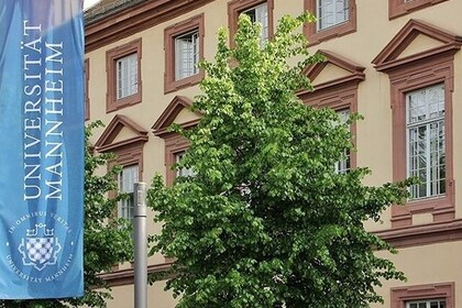 Nahaufnahme der Universität Mannheim. Links daneben ist eine Flagge mit dem Logo zu sehen. 
