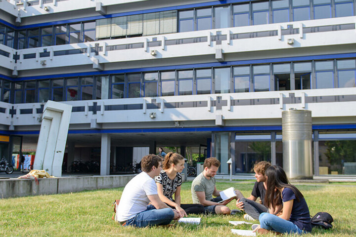 Studierende sitzen auf dem Rasen vor A 5