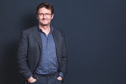 Peter Vorderer im Anzug vor blau-grauem Hintergrund.
