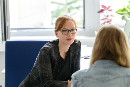 Eine Mitarbeiterin spricht im persönlichen Gespräch mit einer Studentin.