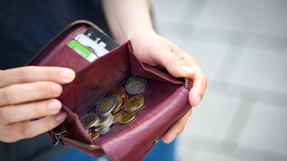 Portmonee Eine Hand öffnet ein rotes Portemonnaie mit Geldmünzen