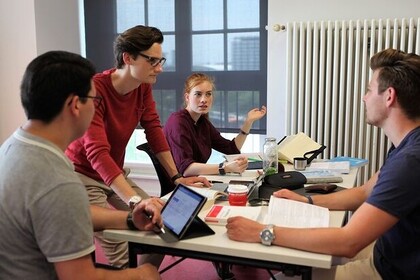 Vier Studierende sitzen an einem Tisch und unterhalten sich miteinander. 