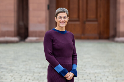 Portrait von Tina In-Albon. Sie trägt ein lila-blaues Kleid.