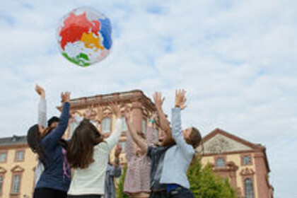 Bild von Studierenden die Ball mit Weltkarte hochwerfen