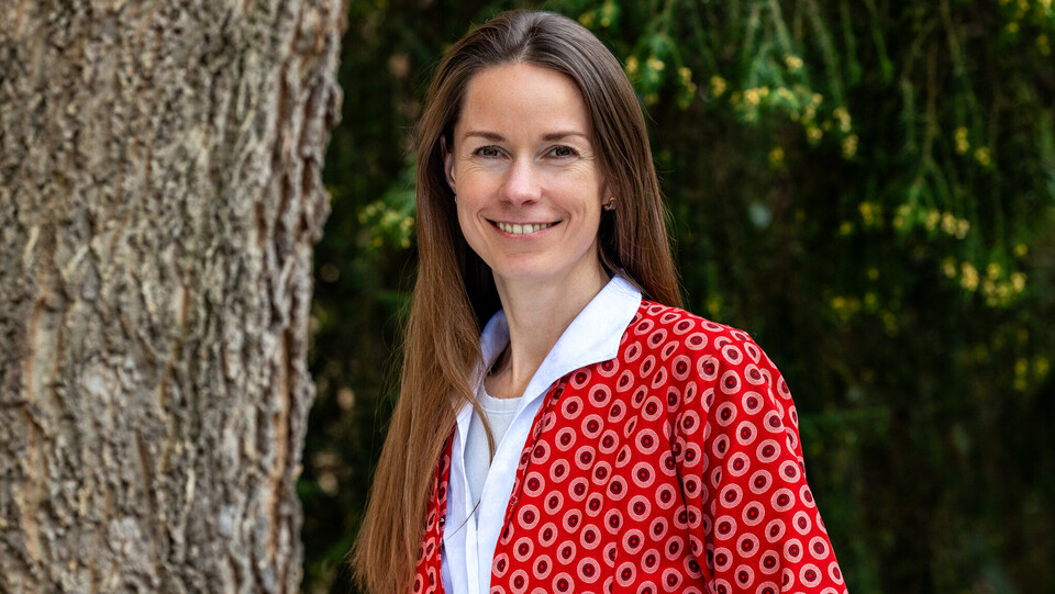Prof. Dr. Ilze Plavgo. Sie steht lächelnd vor einem Baum und trägt einen rot gemusterten Blazer.