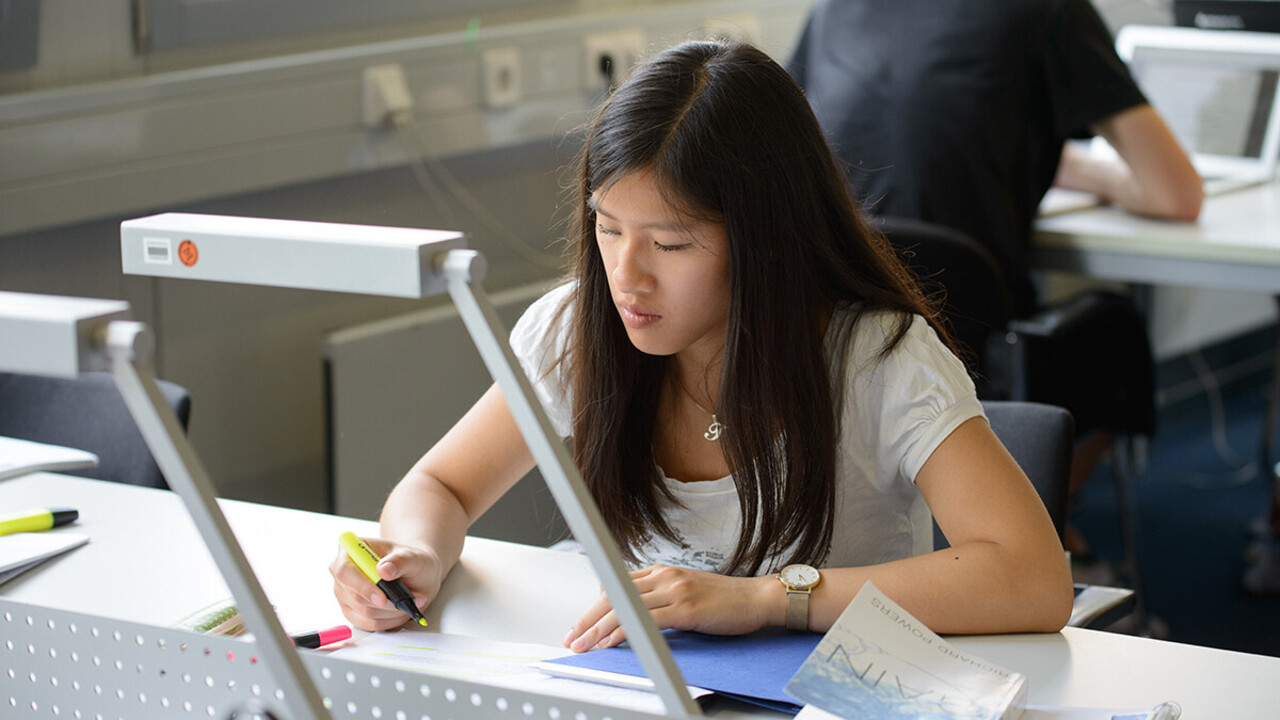 Eine Studierende sitzt an einem Schreibtisch in der A5-Bibliothek und lernt.