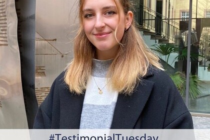 Porträt der Soziologiestudientin und Sportstipendiatin Leia Braunagel. Sie trägt einen Pulli mit grauen und weißen Blockstreifen und eine weite dunkle Blazer-Jacke. Ihre blonden Haare sind schulterlang. Sie lacht freundlich in die Kamera. Link: Insta Testimonial Tuesday Leia Braunagel