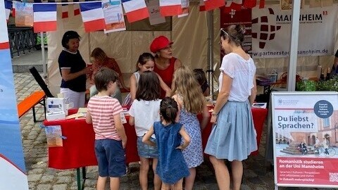 Eine Gruppe von Kindern vor dem Stand der Deutsch-Französischen Vereinigung und des Romanischen Seminars beim Bal Populaire.