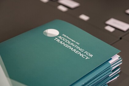 Stapel dunkelgrüner Ordner mit weißem Aufdruck und Logo von Accounting for Transparency