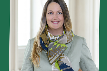 Laura Marie Edinger-Schons hat lange blonde Haare. Sie trägt einen hellblauen Blazer und einen bunten Schal. Oben links steht "Green Uni Ma".