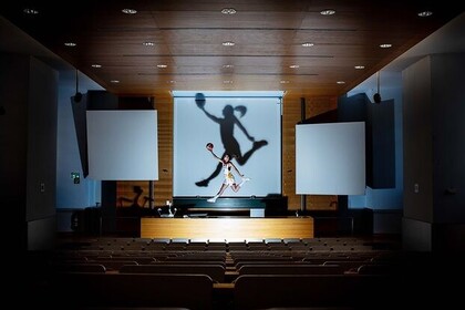 Britta Daub springt im Zentrum eines Hörsaals und hält einen Ball in der Hand. 