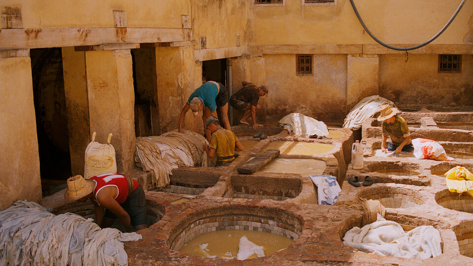 Chouara Tanneries Mehrere Männer arbeiten unter freiem Himmel in einer marokkanischen Färberei.