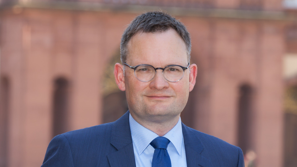 Portrait von Philipp Gassert. Er trägt einen blaugrauen Anzug mit blauer Krawatte. 