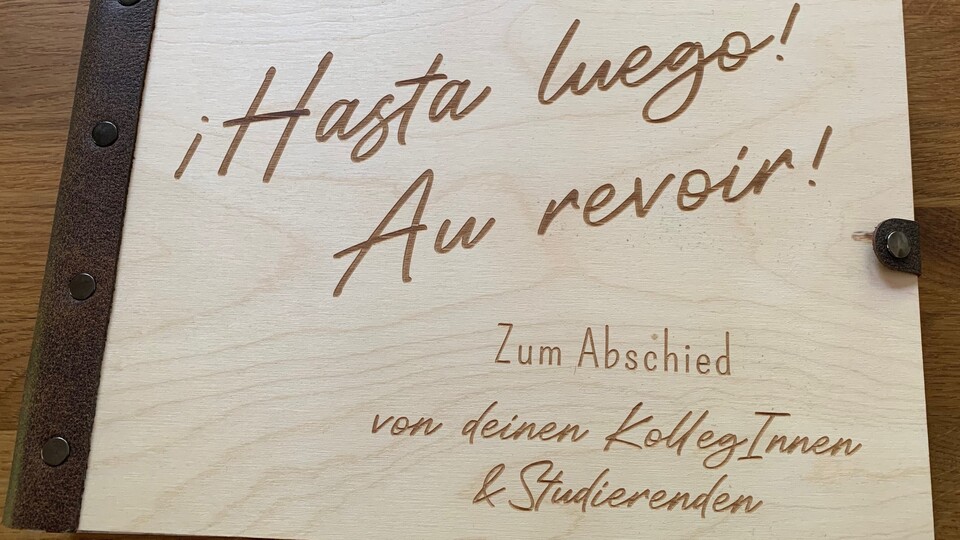 Buch in einem hölzernen Einband mit der Aufschrift: "Hasta Luego!", "Au revoir!"