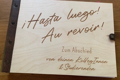 Buch in einem hölzernen Einband mit der Aufschrift: "Hasta Luego!", "Au revoir!"