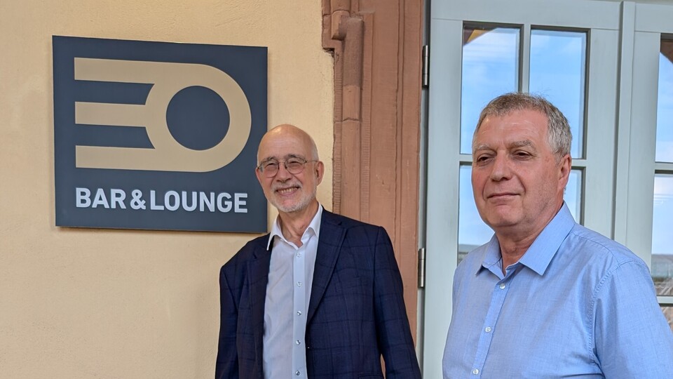 Professor Thomas Puhl und Peter Pahle stehen vor dem Eingang zur Cafeteria EO, an der Wand hängt ein Schild "EO Bar & Lounge".