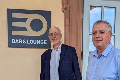 Professor Thomas Puhl und Peter Pahle stehen vor dem Eingang zur Cafeteria EO, an der Wand hängt ein Schild "EO Bar & Lounge".