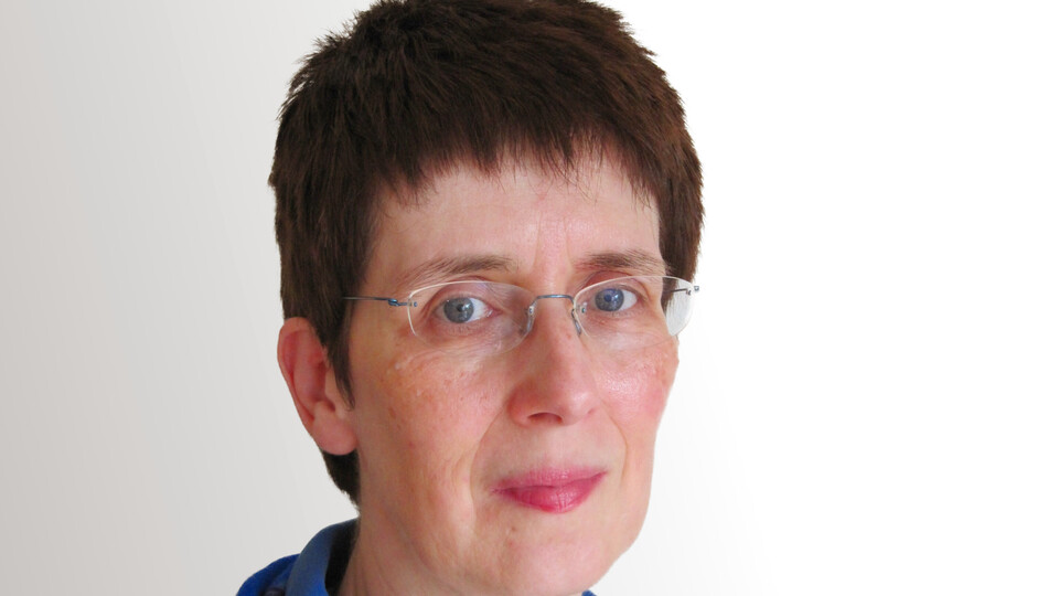 Angela Borgstedt trägt ein blaues Oberteil und eine Brille und lächelt leicht in die Kamera.