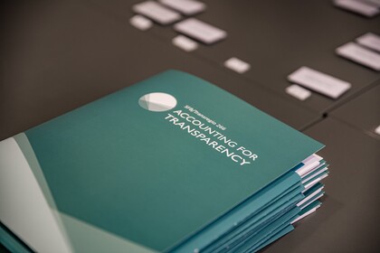 Türkisfarbene Mappen liegen auf einem schwarzen Tisch. Die Mappe haben die weiße Aufschrift "SFB/Transregio 266, Accounting for Transparency".