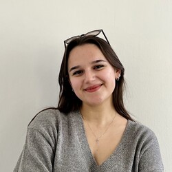 Radina Slavova hat lange braune Haare. Sie trägt einen braunen Pullover und eine schwarze Hose