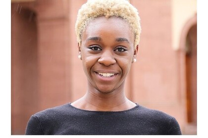 Porträt der französischen Austauschstudentin Martha N'Gandzi im Rahmen der Reihe #testimonialtuesday. Martha N'Gandzi trägt einen schwarzen Pullover, Perlenohrringe und die blondierten Haare kurz. Link: Instagram testimonialtuesday