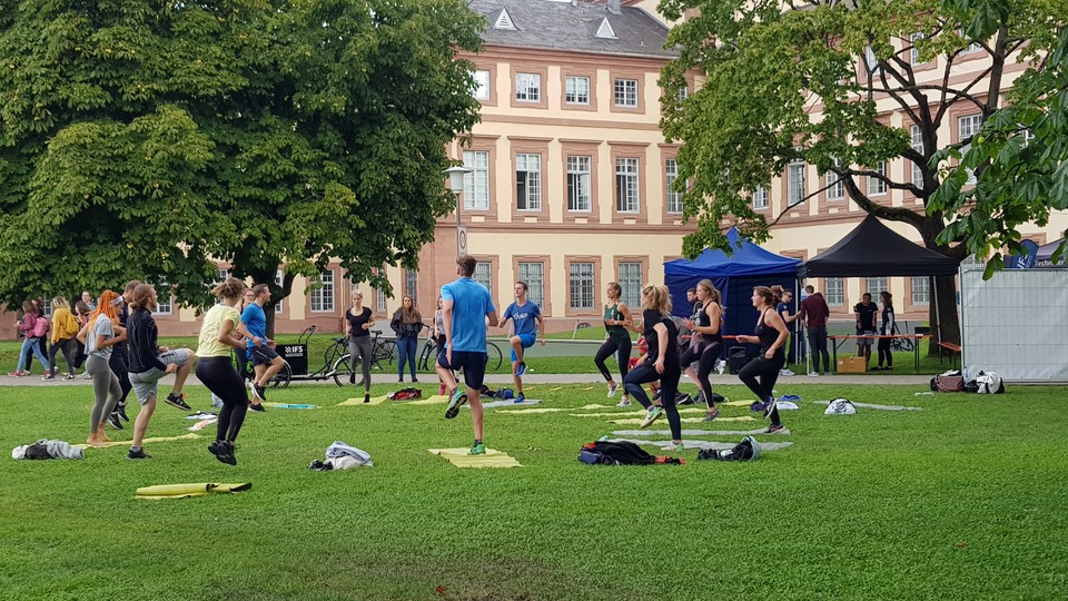 Mehrere Studierende machen auf der Mensawiese Sport. 