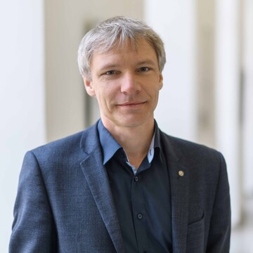 Ein Bild von Prof. Dr. Stefan Münzer. Er hat kurze graue Haare und trägt ein dunkelblaues Hemd mit einem dunklen Jackett.