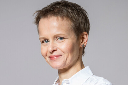 Portrait von Coprmelia Ruhe. Sie trägt eine weiße Bluse und lächelt.