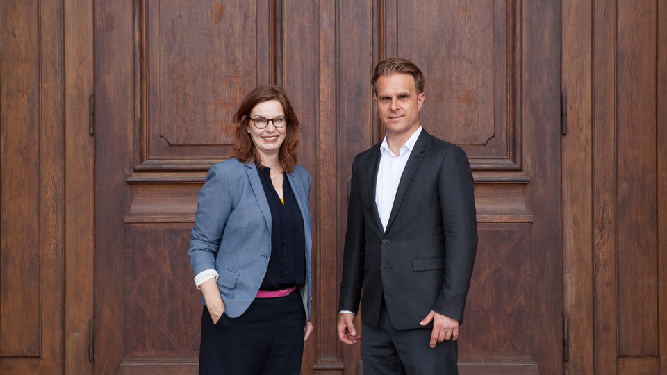Florian Stahl und Sabine Gehrlein stehen vor einer großen Holztür. 