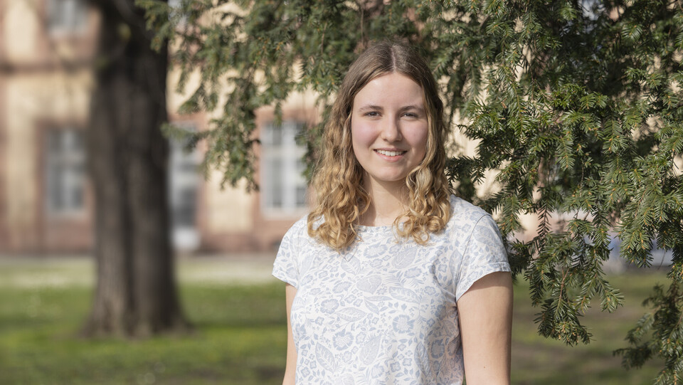 Laura Schmitt. Laura Schmitt trägt eine weiße Bluse und lächelt.