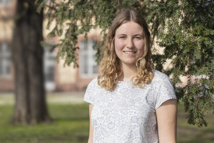 Laura Schmitt. Laura Schmitt trägt eine weiße Bluse und lächelt.