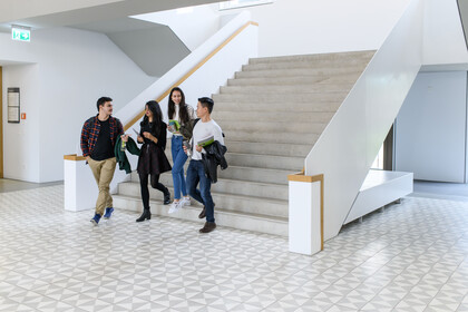 Vier Studierende laufen eine Treppe des B6-Bauteils der Uni Mannheim runter.