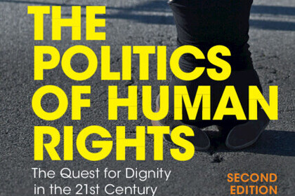 person kneeling with her hands behind her head in front of police