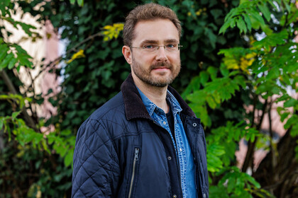 Prof. Dr. Ivan Balykin in blauer Jacke vor grünen Pflanzen.